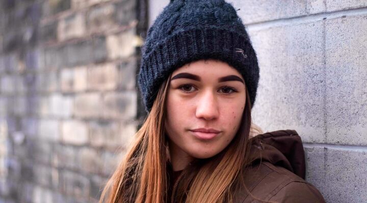 Teenage Girl Wearing Beanie Standing Against Wall With Serious Expression